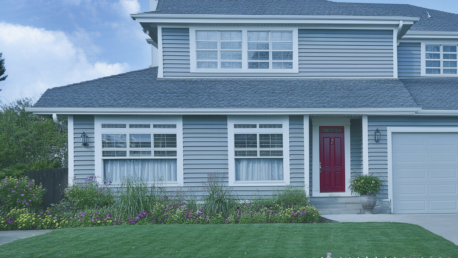 Front exterior with a red door, clipped lawn, and maintained flower beds